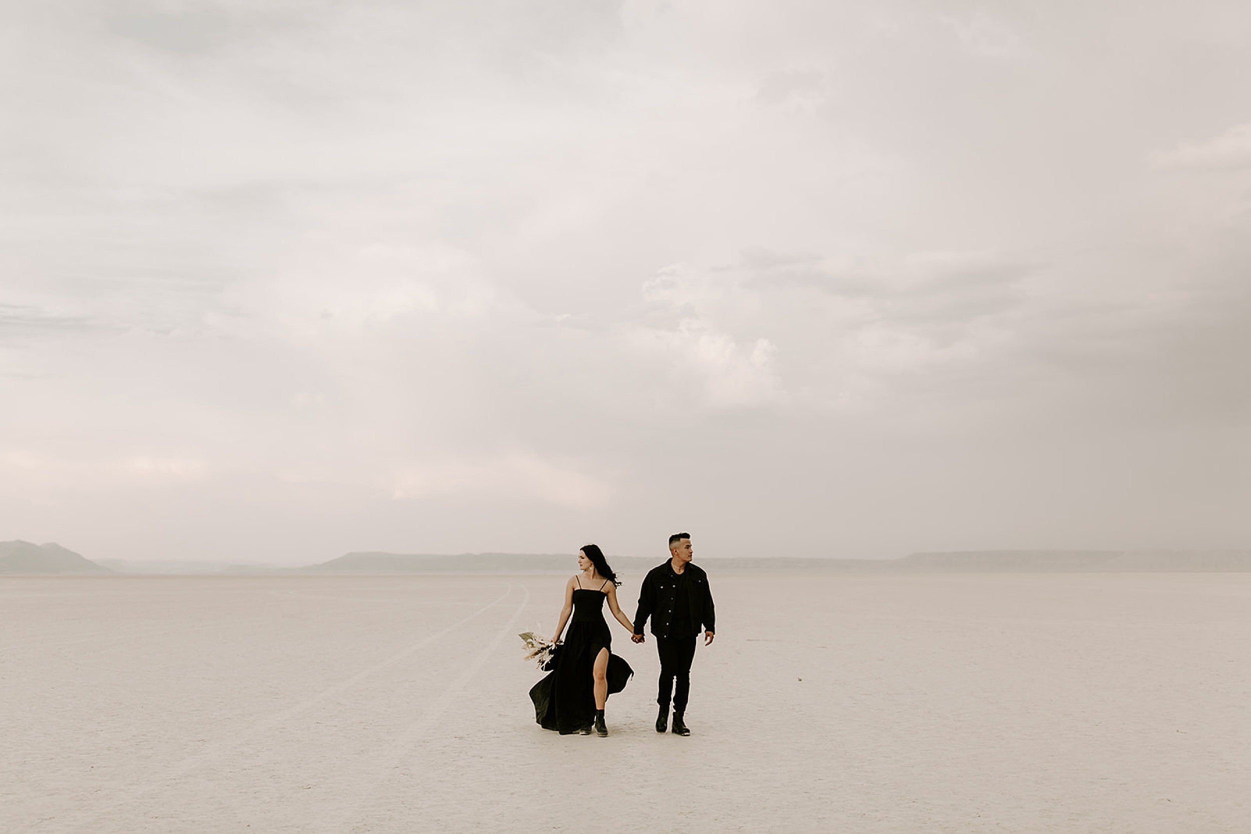 couple holding hands and walking in desert