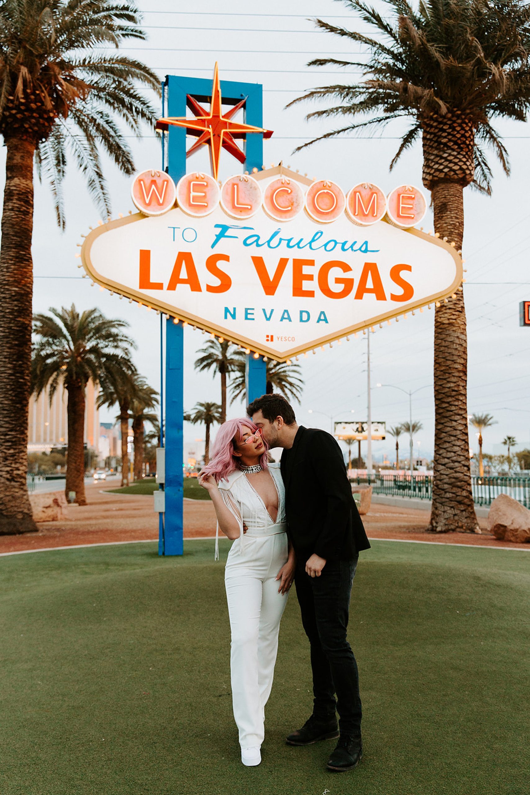 bride and groom kissing in front of las vegas sign