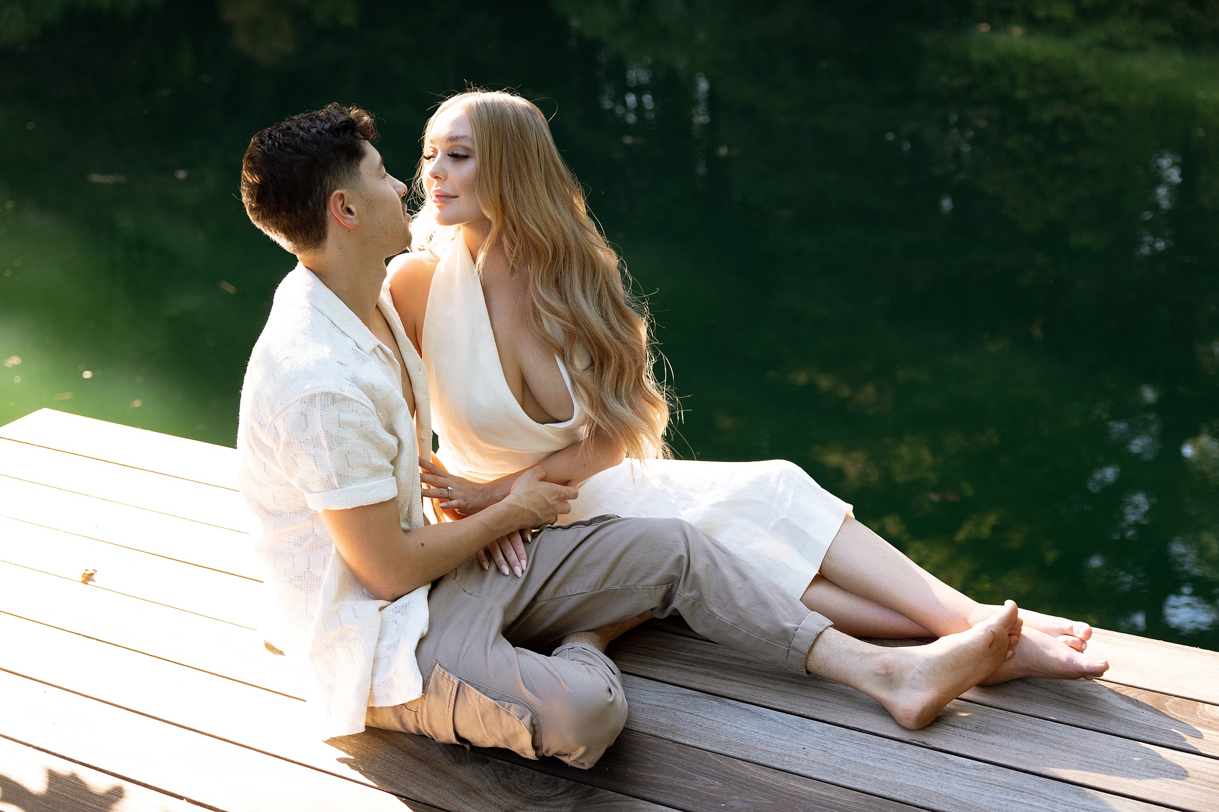 lake engagement photos with scenic greenery trees and a man and woman laying on a dock