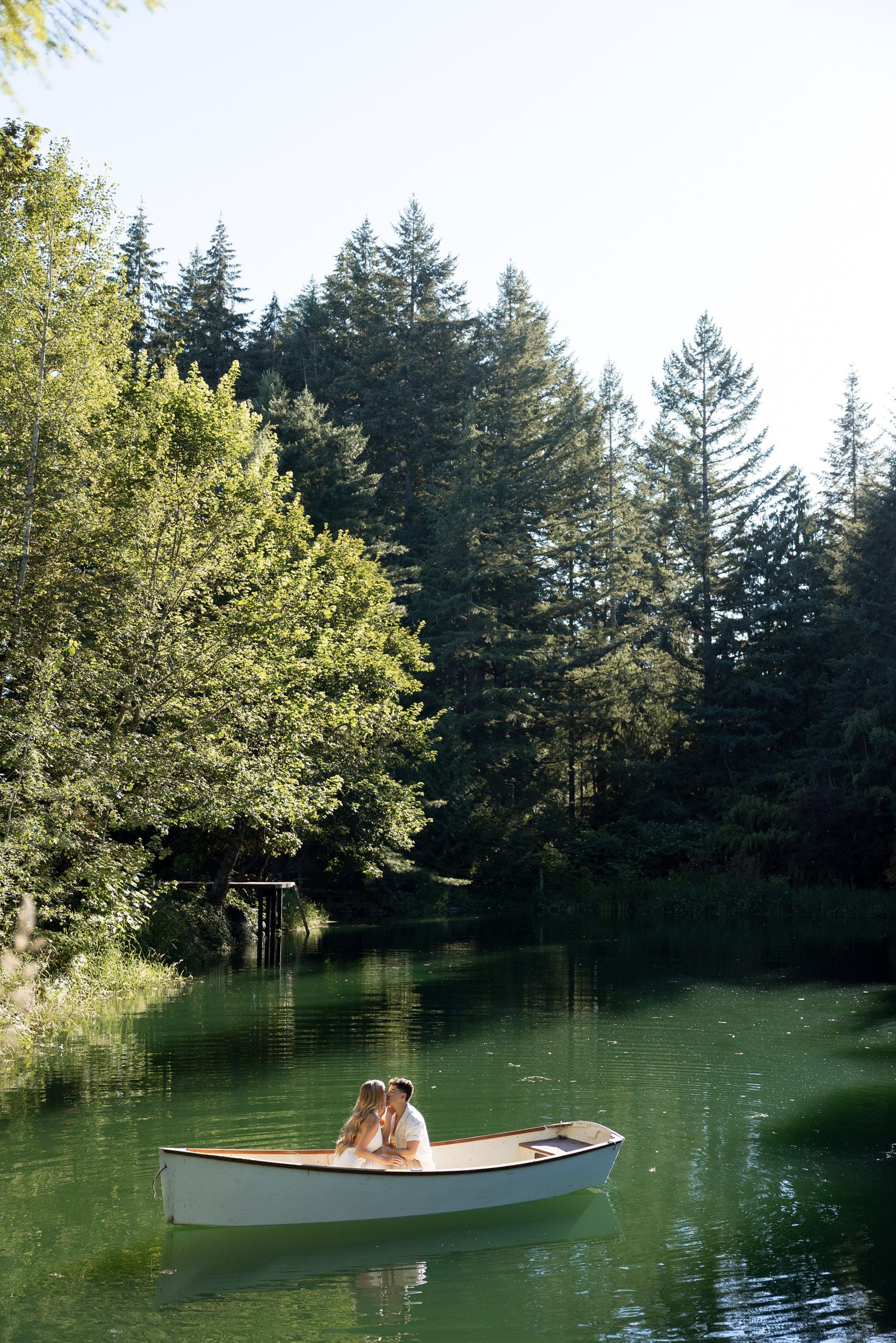 lake engagement photos in scenic greenery trees and a white small row boat