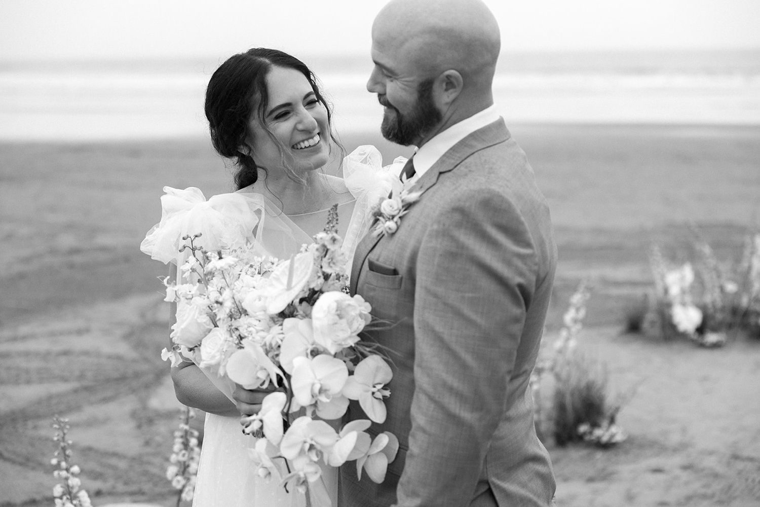 A bride holding an orchid bouquet and groom at their Oregon coast elopement.