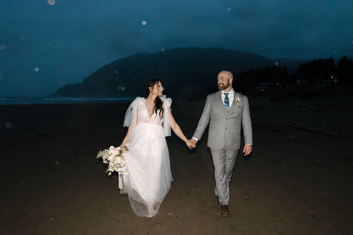 bride and groom walking in the rain at their Oregon coast elopement