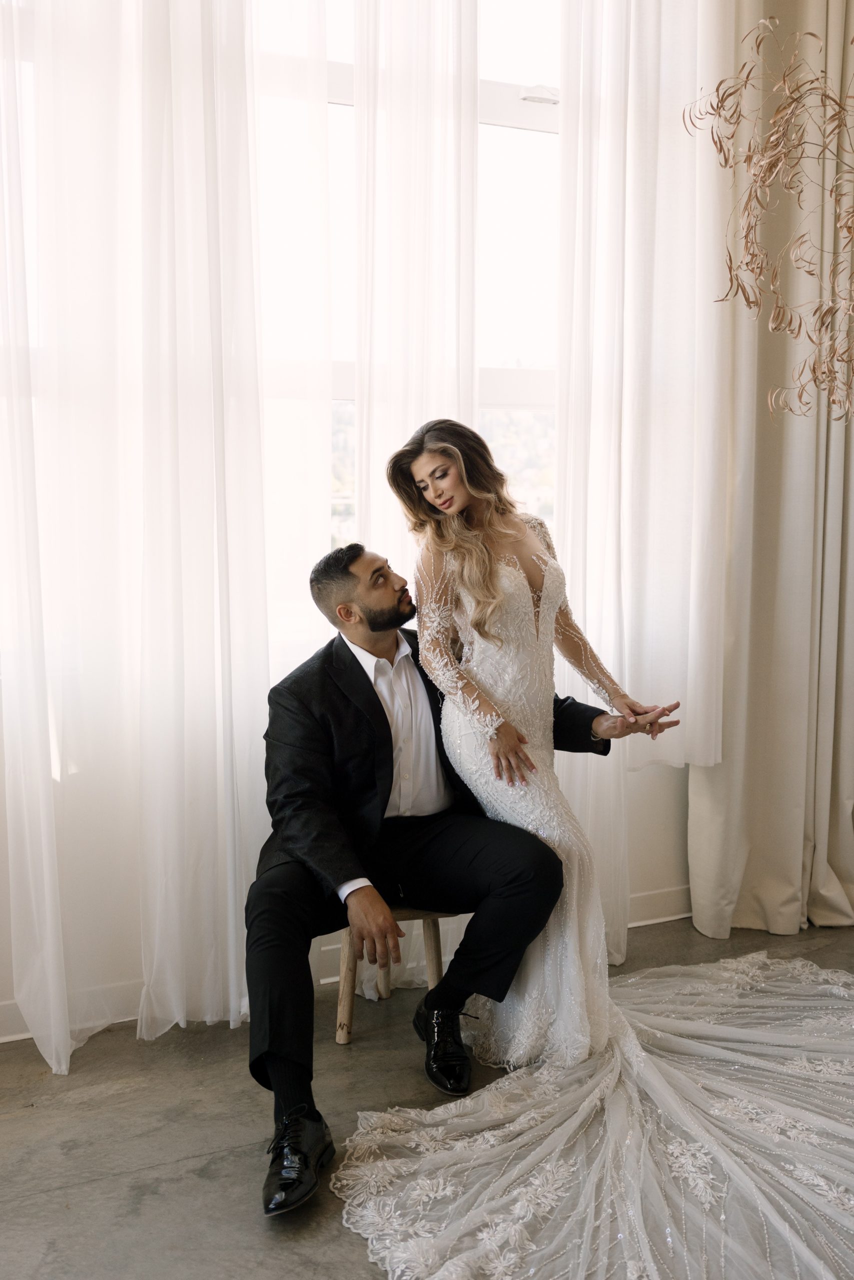 bride in white beaded maxi gown and groom in a black suite posing for thier bridal portraits