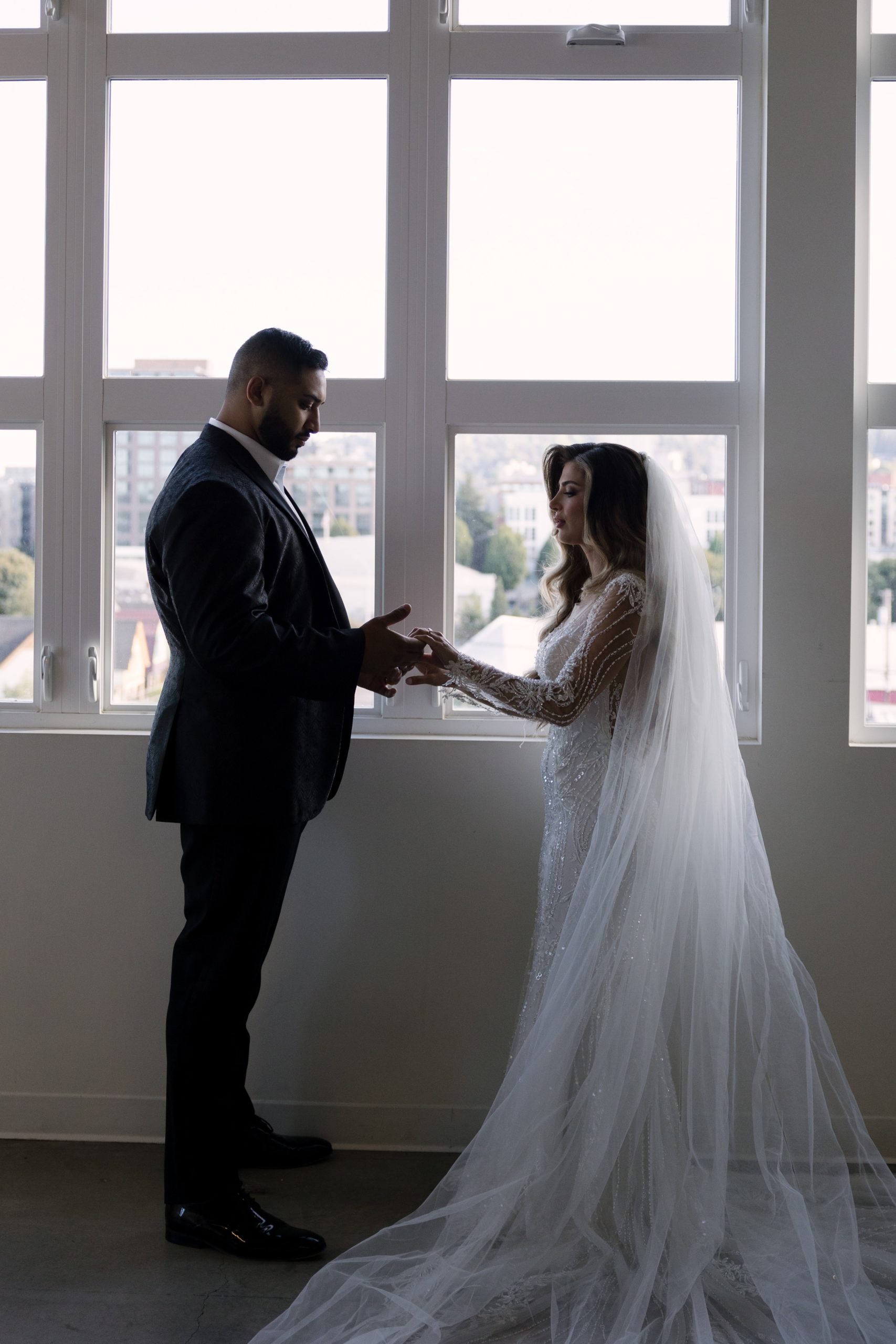 bride in white beaded maxi gown and groom in a black suite holding hands at their bridal portraits